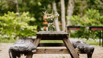 Une table en bois rustique, ornée d’un vase de fleurs au centre, et entourée de deux moutons.
