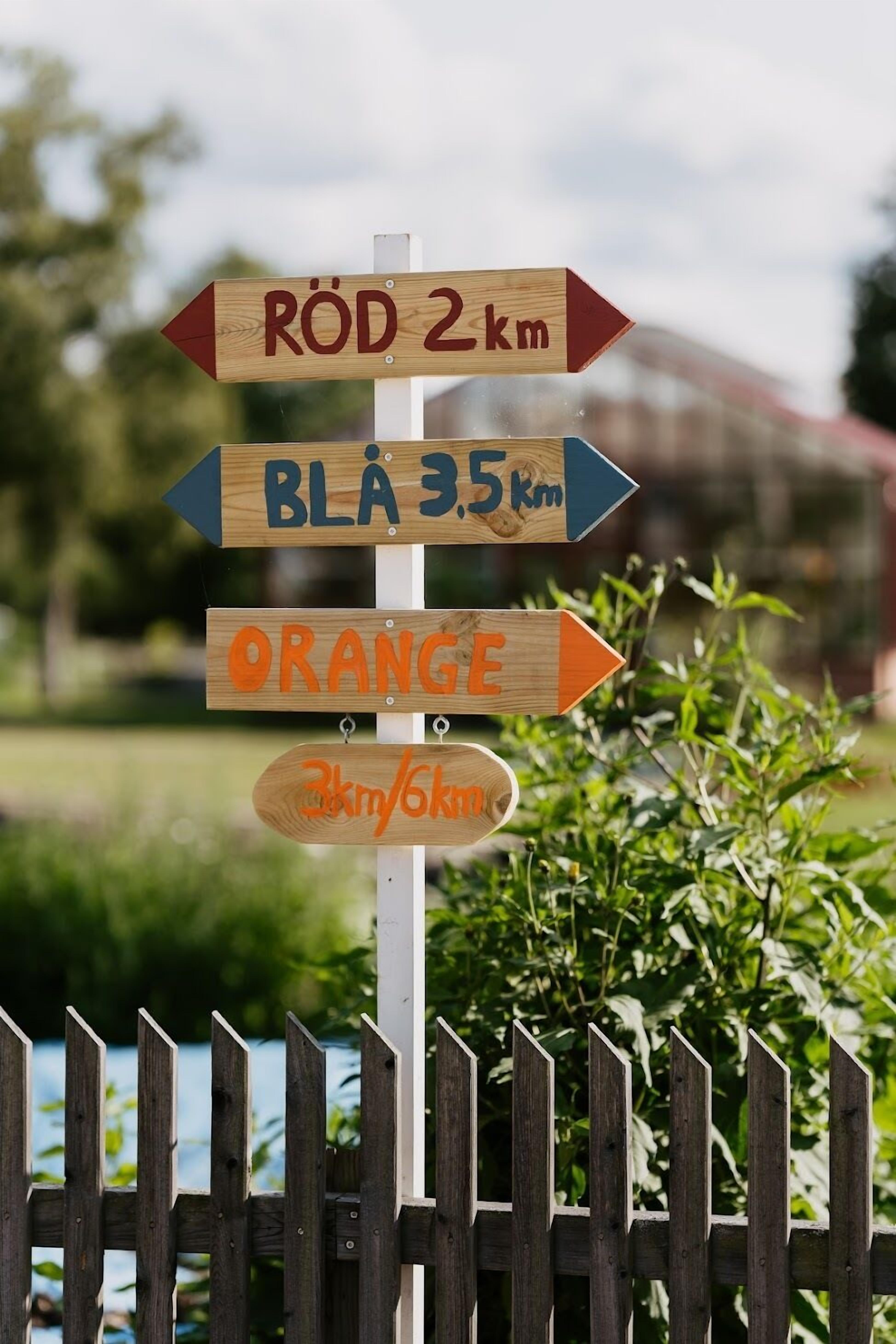 A wooden signpost with directional arrows and distances to various destinations.