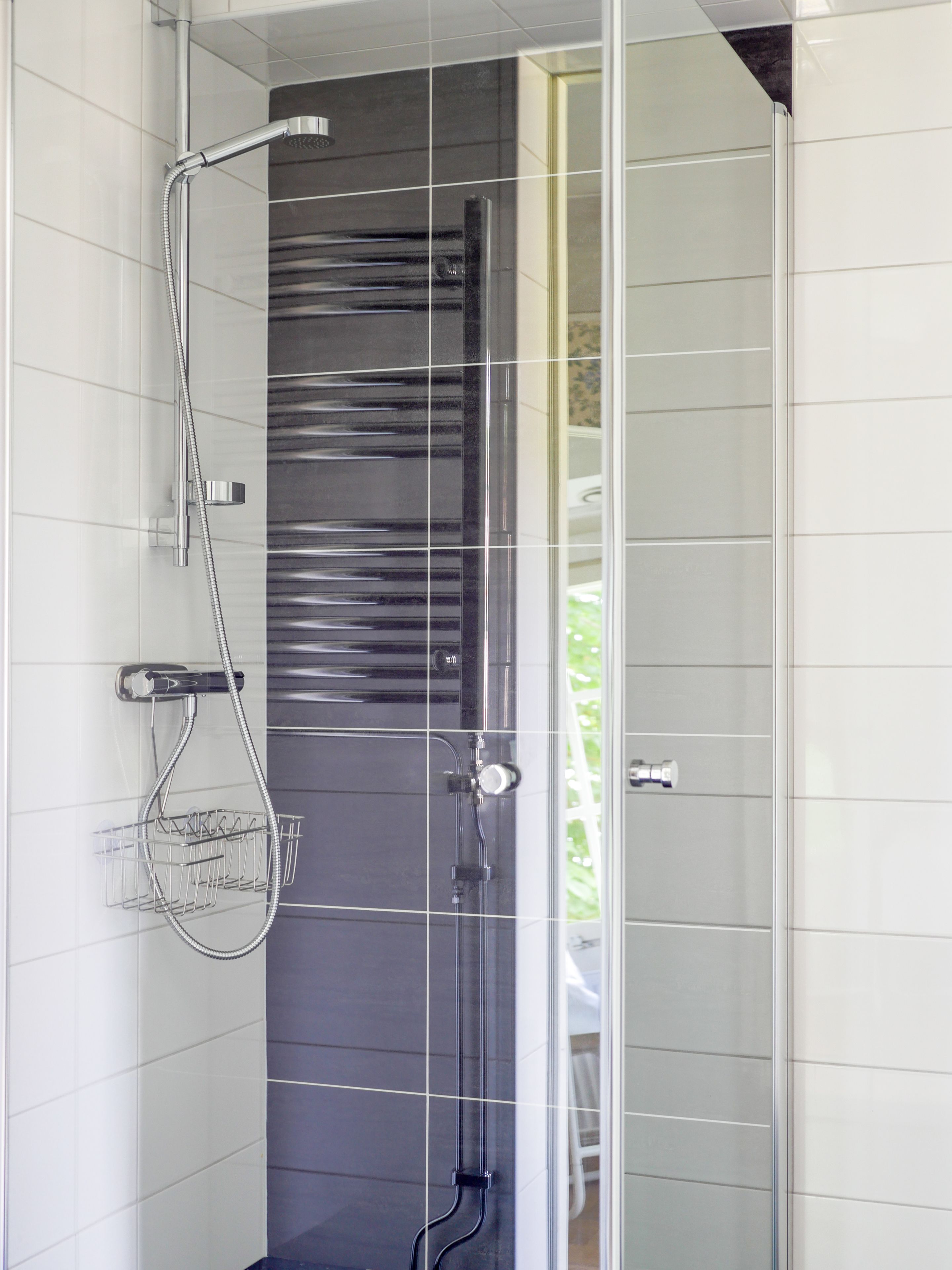A modern shower with a glass door, chrome fixtures, and a towel rack.