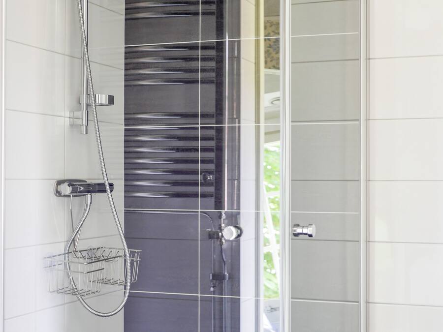 A modern shower with a glass door, chrome fixtures, and a towel rack.