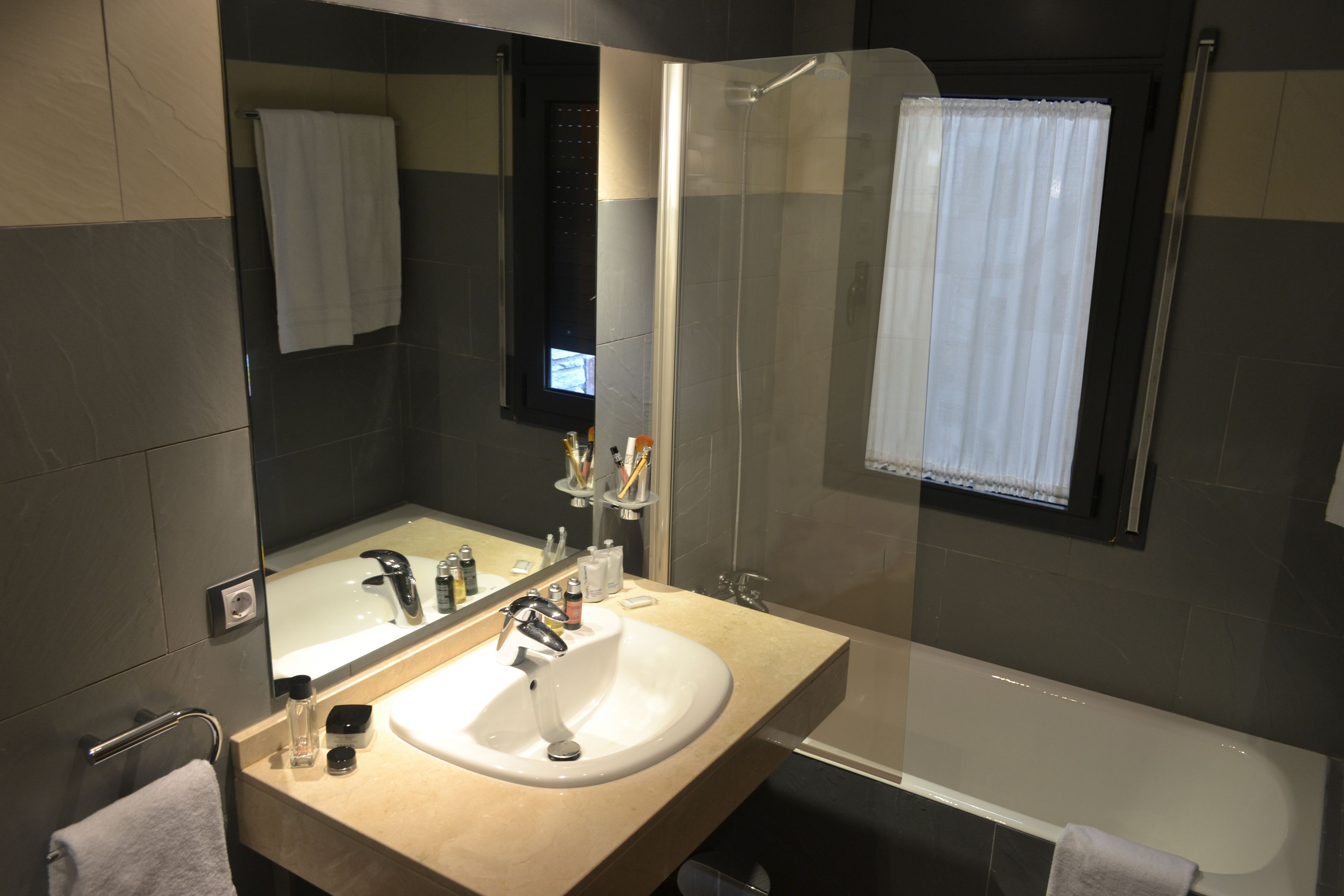 A modern bathroom with a sink, mirror, and shower.