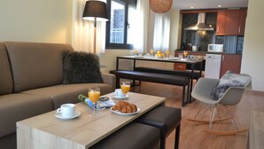 Un salon moderne comprenant un canapé, une table à manger avec des aliments pour le petit-déjeuner, un coin cuisine et un fauteuil à bascule.
