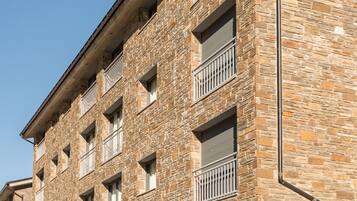 A multi-story building with stone facade, balconies, and a flat roof.