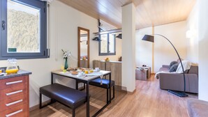 Une cuisine moderne avec une table à manger, un banc et des aliments pour le petit-déjeuner. Le salon comprend un canapé et une lampe.