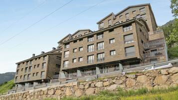 A multi-story hotel with a stone facade, balconies, and a view of the surrounding landscape.