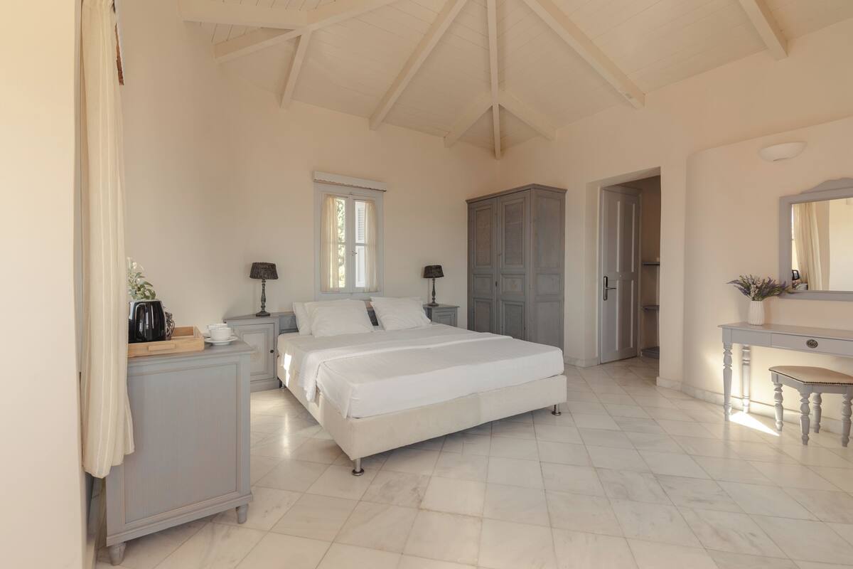 Quarto com uma cama grande, penteadeira, escrivaninha e guarda-roupa.
