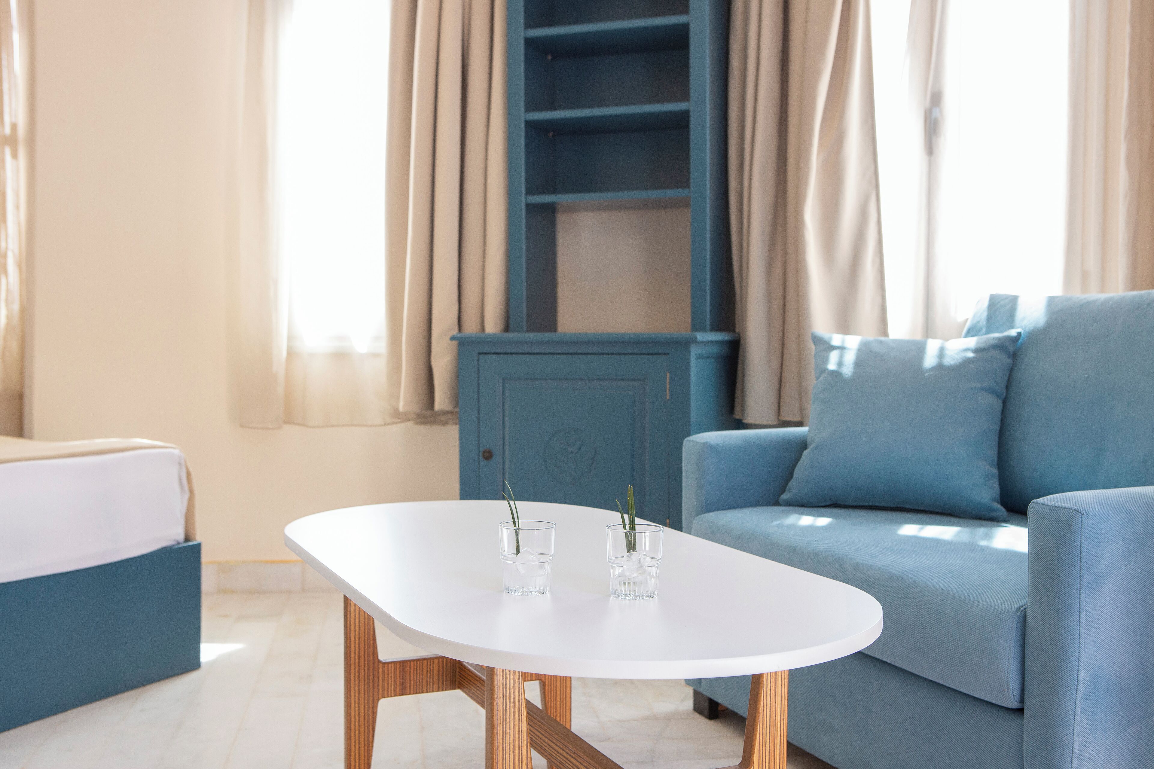 A modern living room with a blue sofa, a white table, and a blue cabinet.