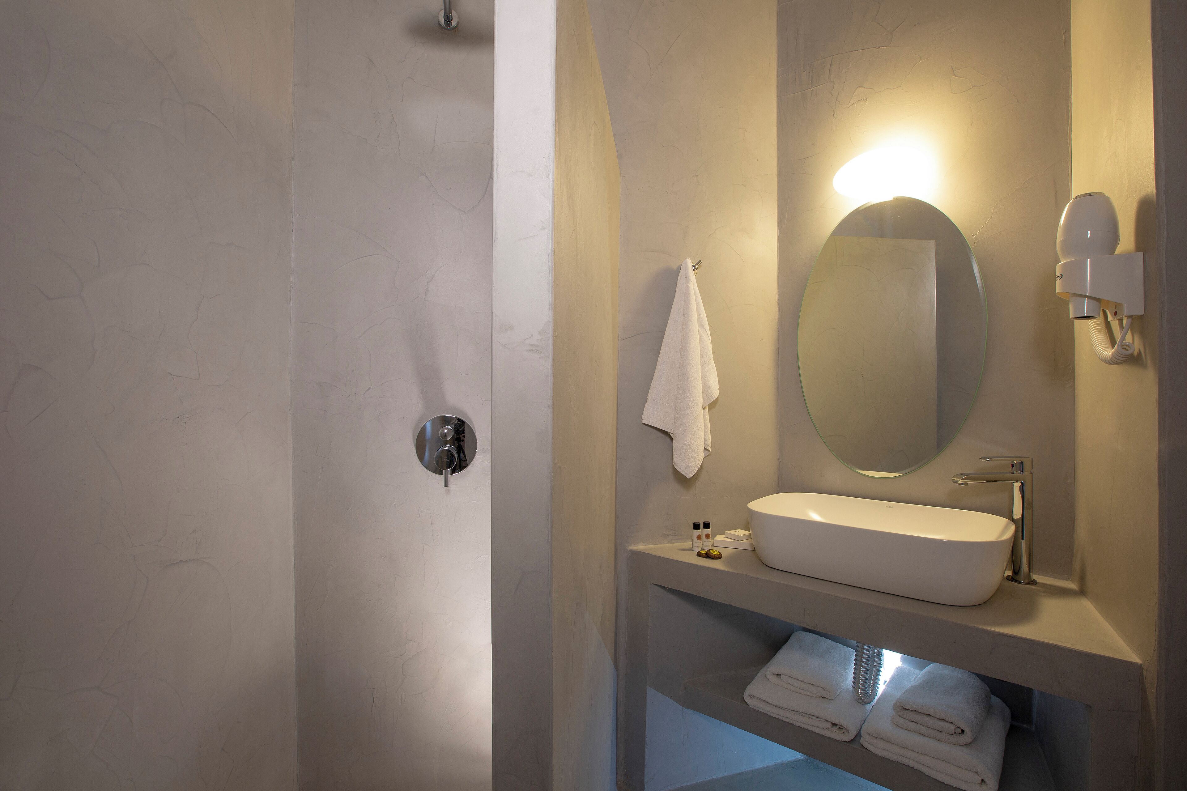 A bathroom with a white sink, a round mirror, and a towel rack.