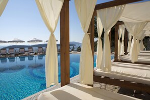 A poolside area with white canopies, lounge chairs, and a clear view of the water. - Red Tower Hotel Lefkada (Lefkada)