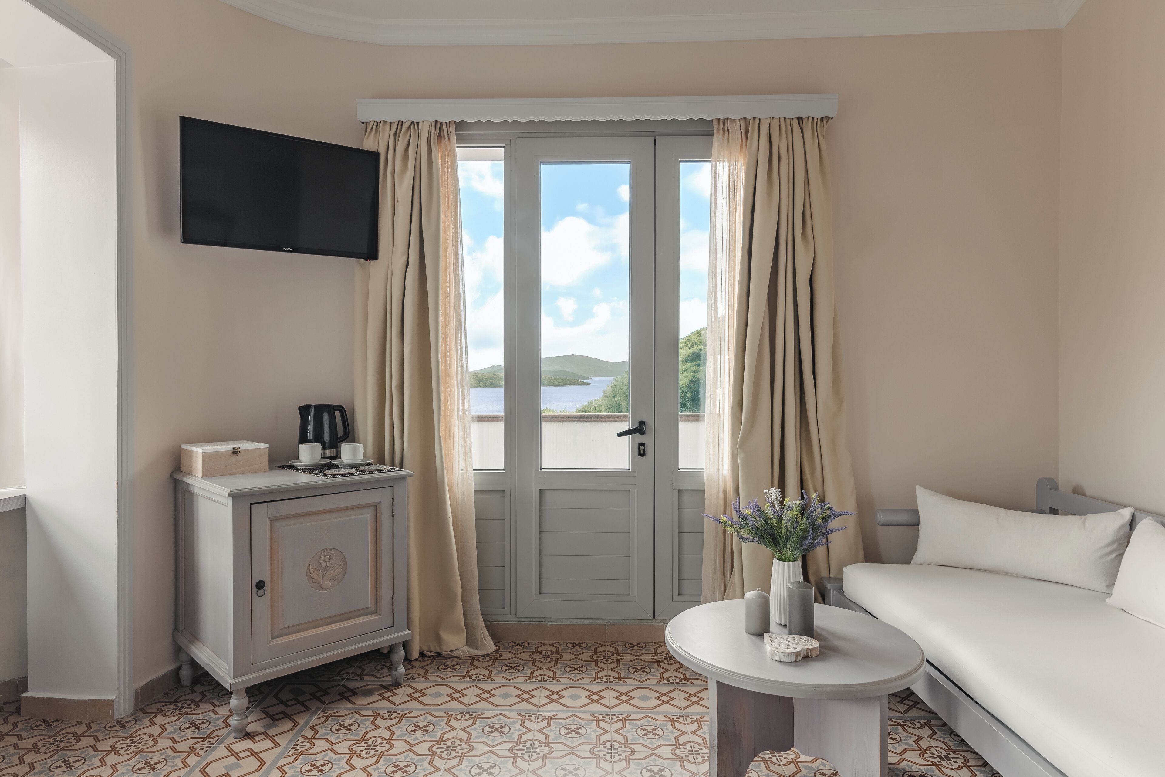 Une chambre d’hôtel avec un lit, une petite table sur laquelle se trouve un vase, une armoire et un téléviseur fixé au mur.