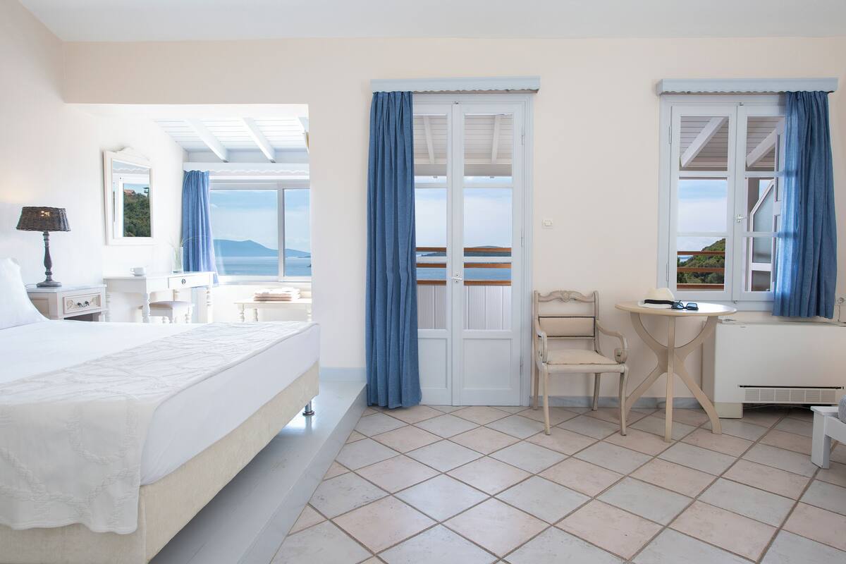 Quarto de hotel com uma cama, uma mesa, uma cadeira e vista para o mar.