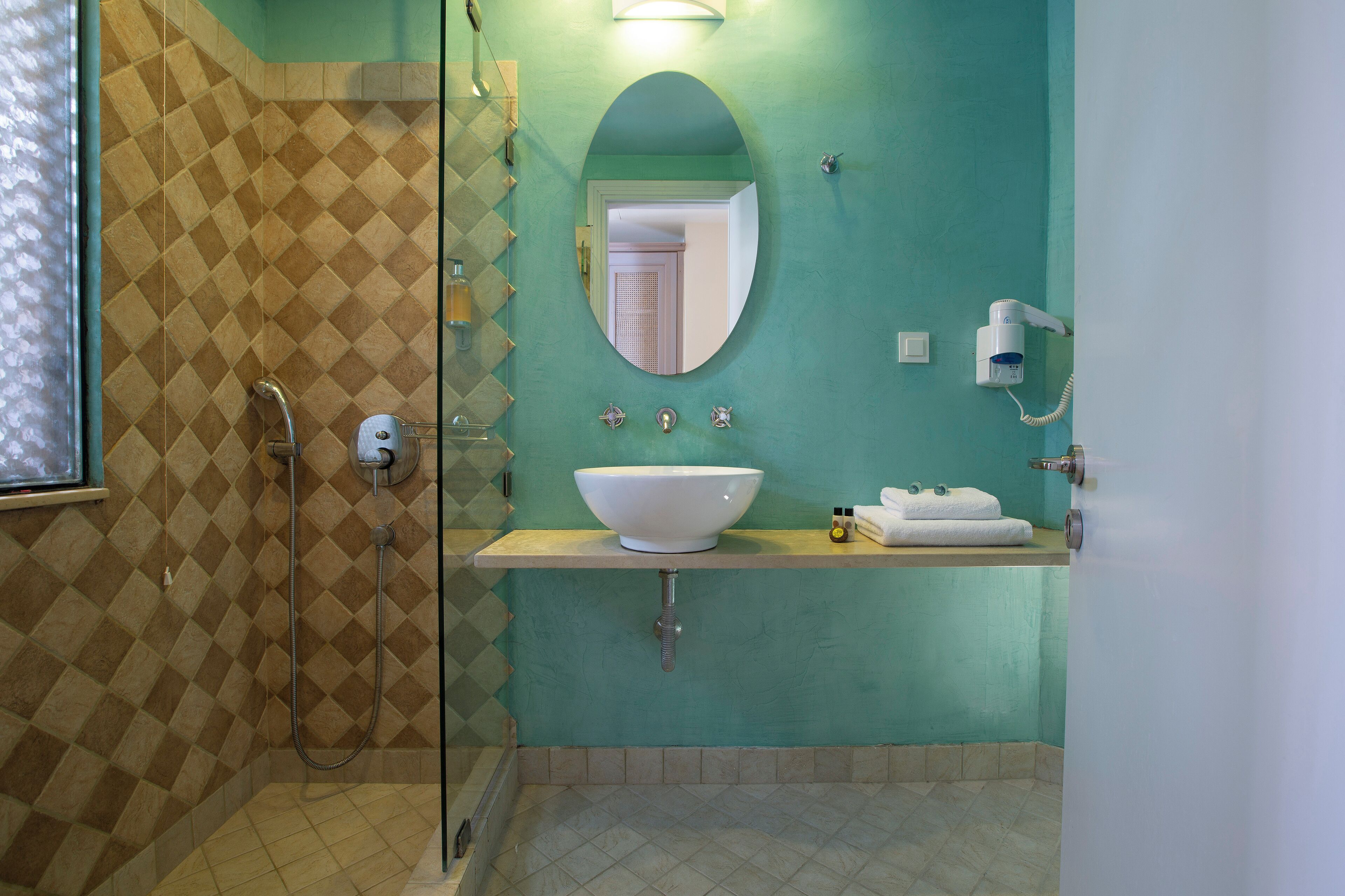 A bathroom with a shower, a sink with a bowl, a mirror, and a towel rack.