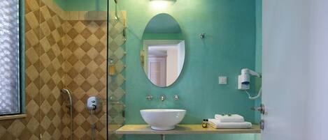 A bathroom with a shower, a sink with a bowl, a mirror, and a towel rack.