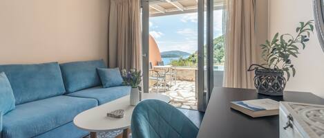 A modern living room with a blue sofa, a round table, and a view of the outdoors through a glass door.