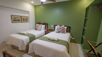 A hotel room with two beds, a ceiling fan, and a green accent wall.