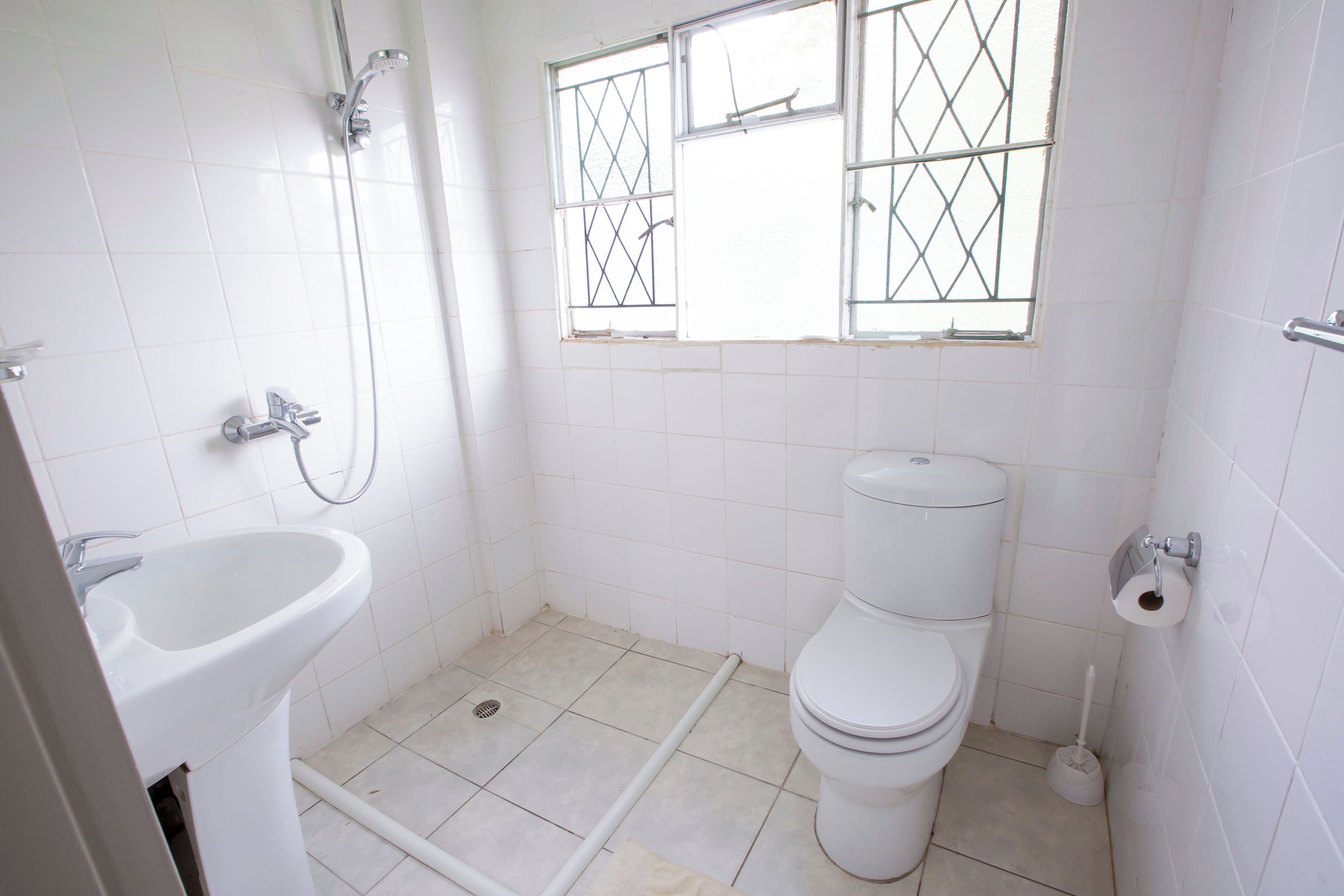 A small, clean bathroom with a toilet, sink, and shower.