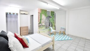 Un dormitorio con cama, una silla, una mesita, un armario y un mural en la pared.