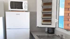 Una cocina compacta con un refrigerador blanco, un microondas y un horno empotrado.