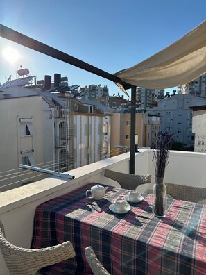 A balcony with a table set for tea, a wicker chair, and a vase with flowers. - Serenity Suit Hotel (Konyaalti)