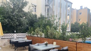 Une terrasse extérieure avec une clôture en bois, une table avec des chaises et un parasol à rayures jaunes.