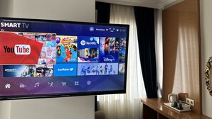 Une chambre d’hôtel équipée d’un grand téléviseur à écran plat affichant une interface de télévision connectée, donnant accès à divers services de diffusion en continu.