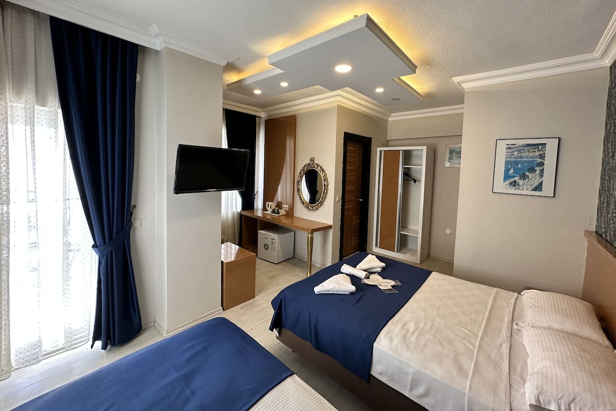 Een hotelkamer met twee bedden, een bureau met een computer, een televisie en een spiegel.