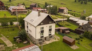 Een landelijk dorp met een mix van traditionele en moderne huizen, omgeven door groene velden en heuvels.
