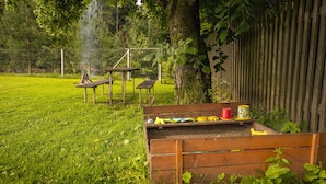Een houten bank met vuurkorf en picknicktafel in een gazon.