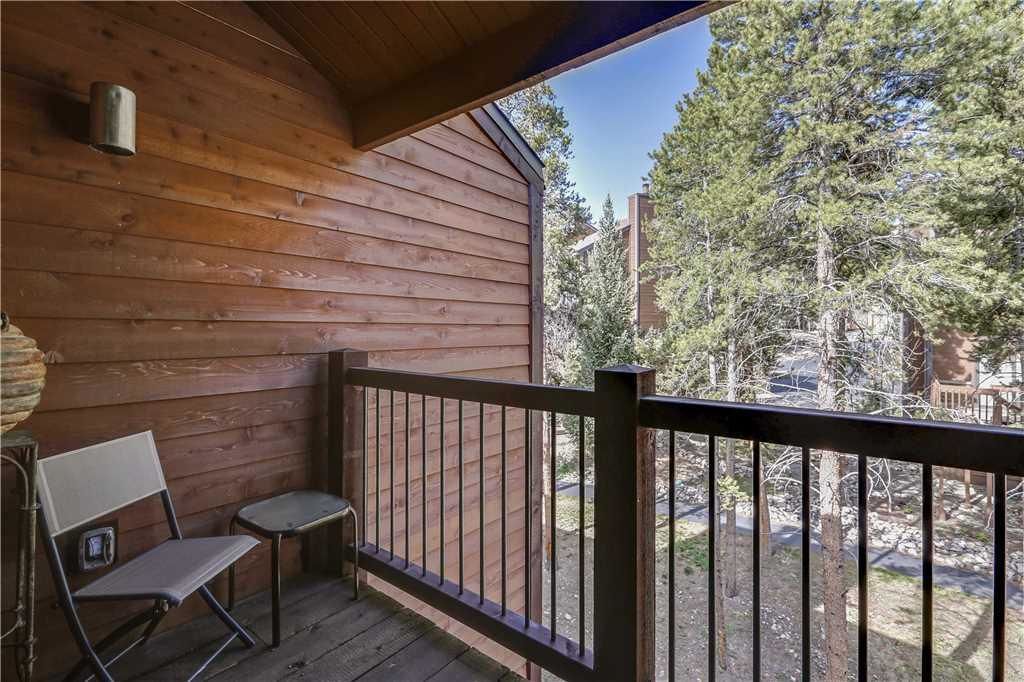Une cabane en bois dotée d’un balcon, d’un banc et d’une petite table.
