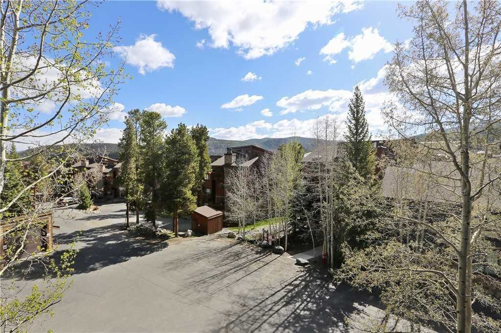A residential area with a paved driveway, wooden cabins, and a mountain backdrop.