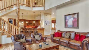 A spacious living area with a leather sofa, a coffee table, and a staircase leading to an upper level.