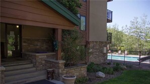 A two-story house with a stone facade, a covered porch, and a swimming pool. - Winterwood 3 Town House (Steamboat Springs)