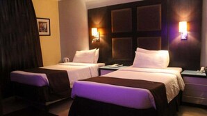 A hotel room with two beds, a nightstand, and wall-mounted lamps. - Villa Angellia Boutique Hotel Victoria Island (Lagos)