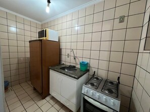A compact kitchen with a refrigerator, a sink, a gas stove, and cabinets. - DiRoma International Resort Via Caldas (Caldas Novas)