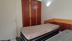 Une chambre à coucher comprenant un lit, une armoire et un luminaire fixé au mur.