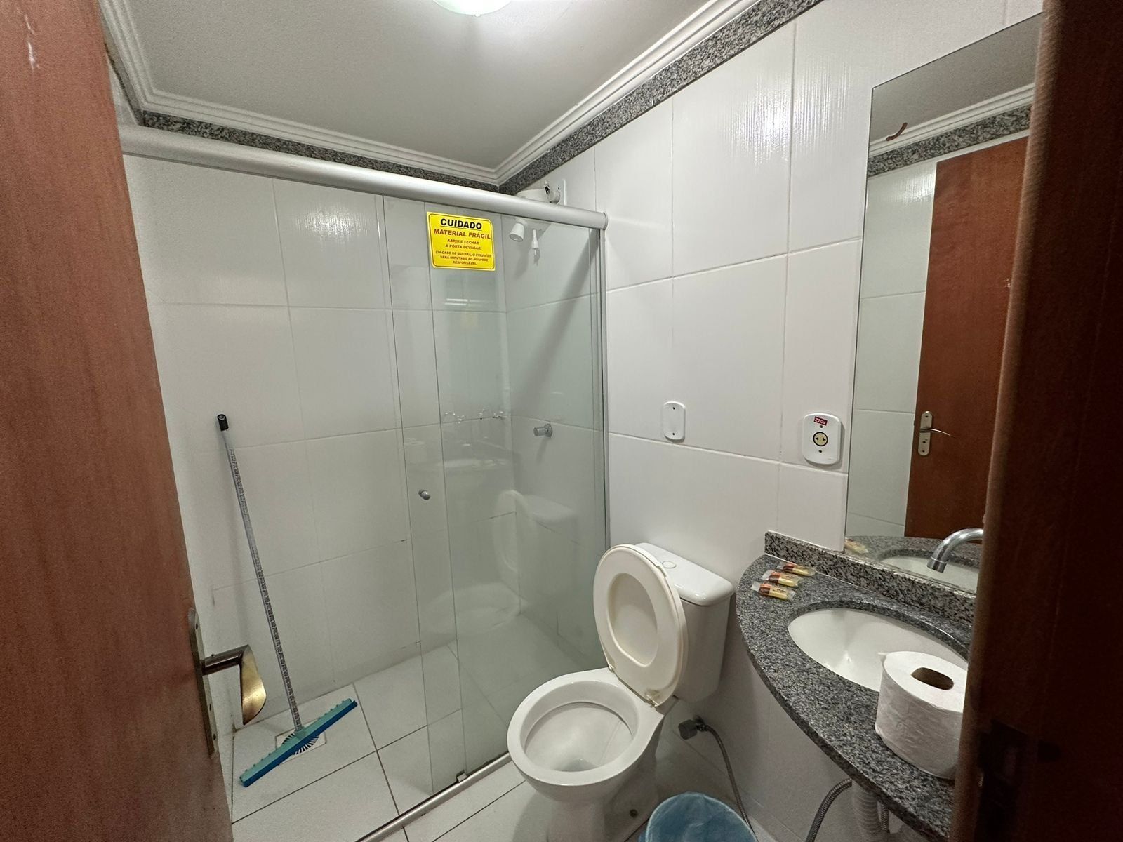A bathroom with a shower, toilet, sink, and a mirror.