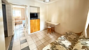 A room with a bed, a TV, a kitchenette, and a ceiling fan. - DiRoma International Resort Via Caldas (Caldas Novas)