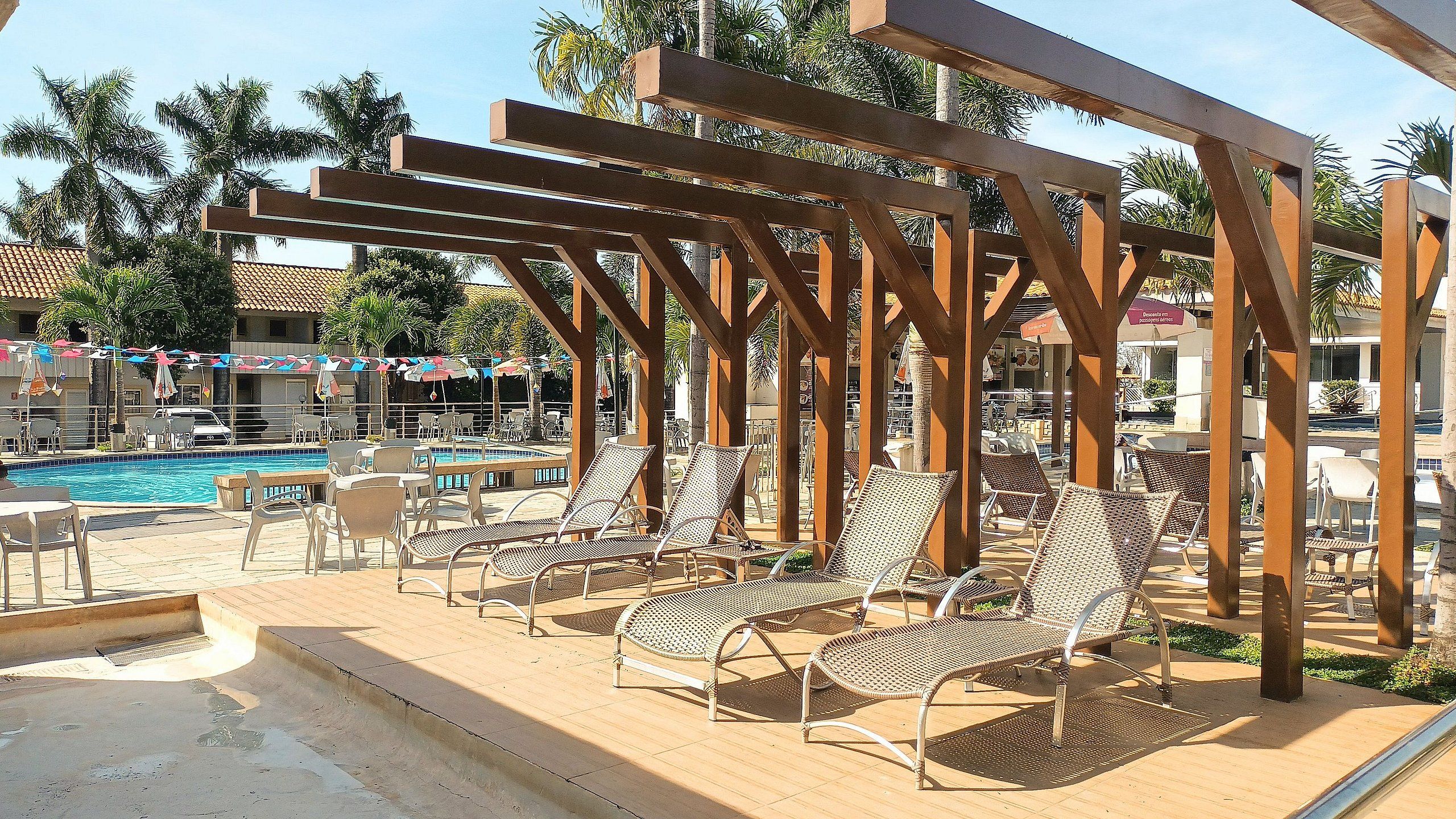 A poolside area with lounge chairs, a pool, and a pergola structure.