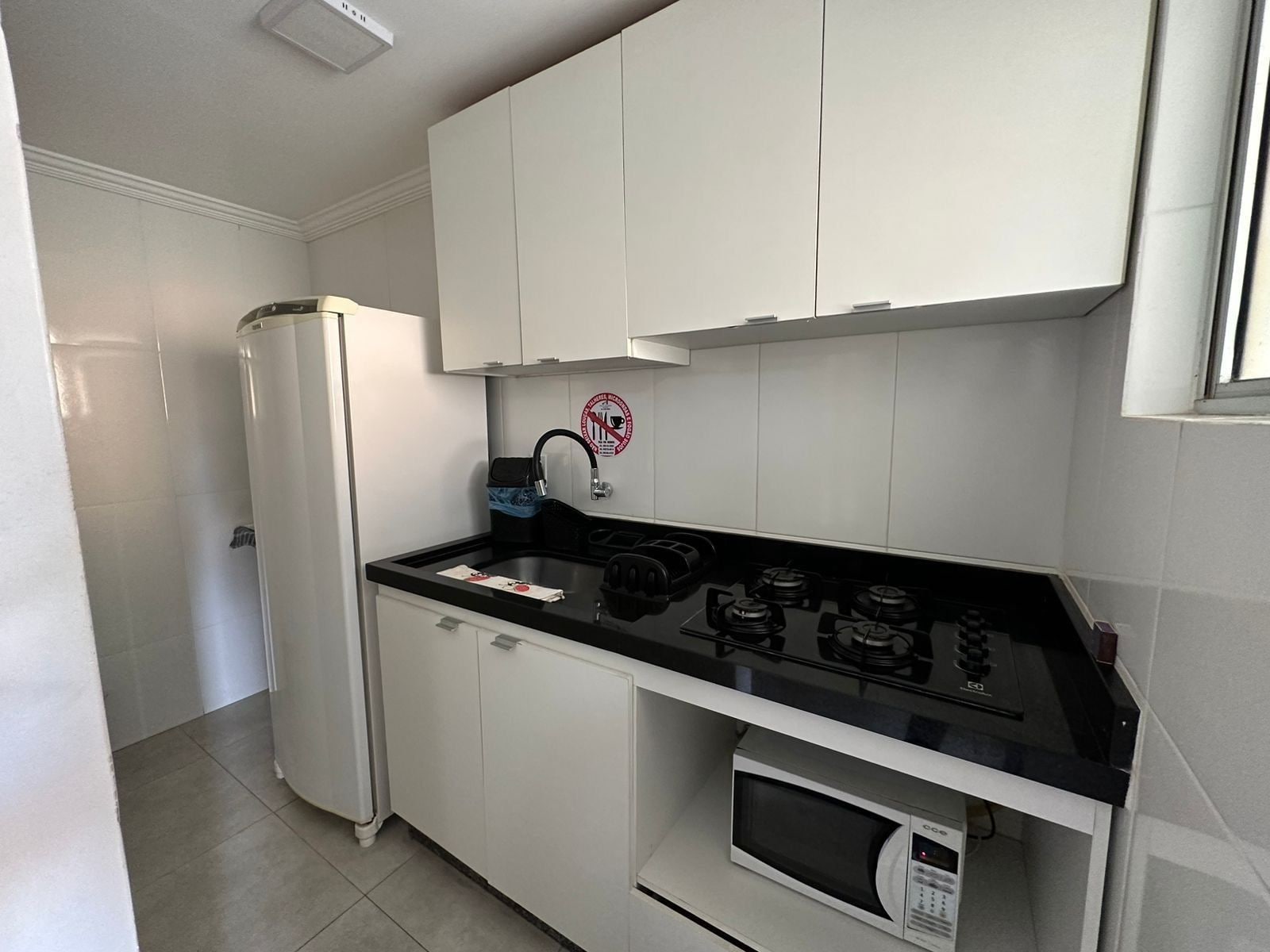 A compact kitchen with white cabinets, a black countertop, a built-in microwave, and a gas stove.