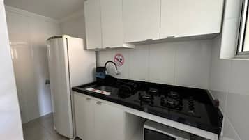 A compact kitchen with white cabinets, a black countertop, a built-in microwave, and a gas stove.
