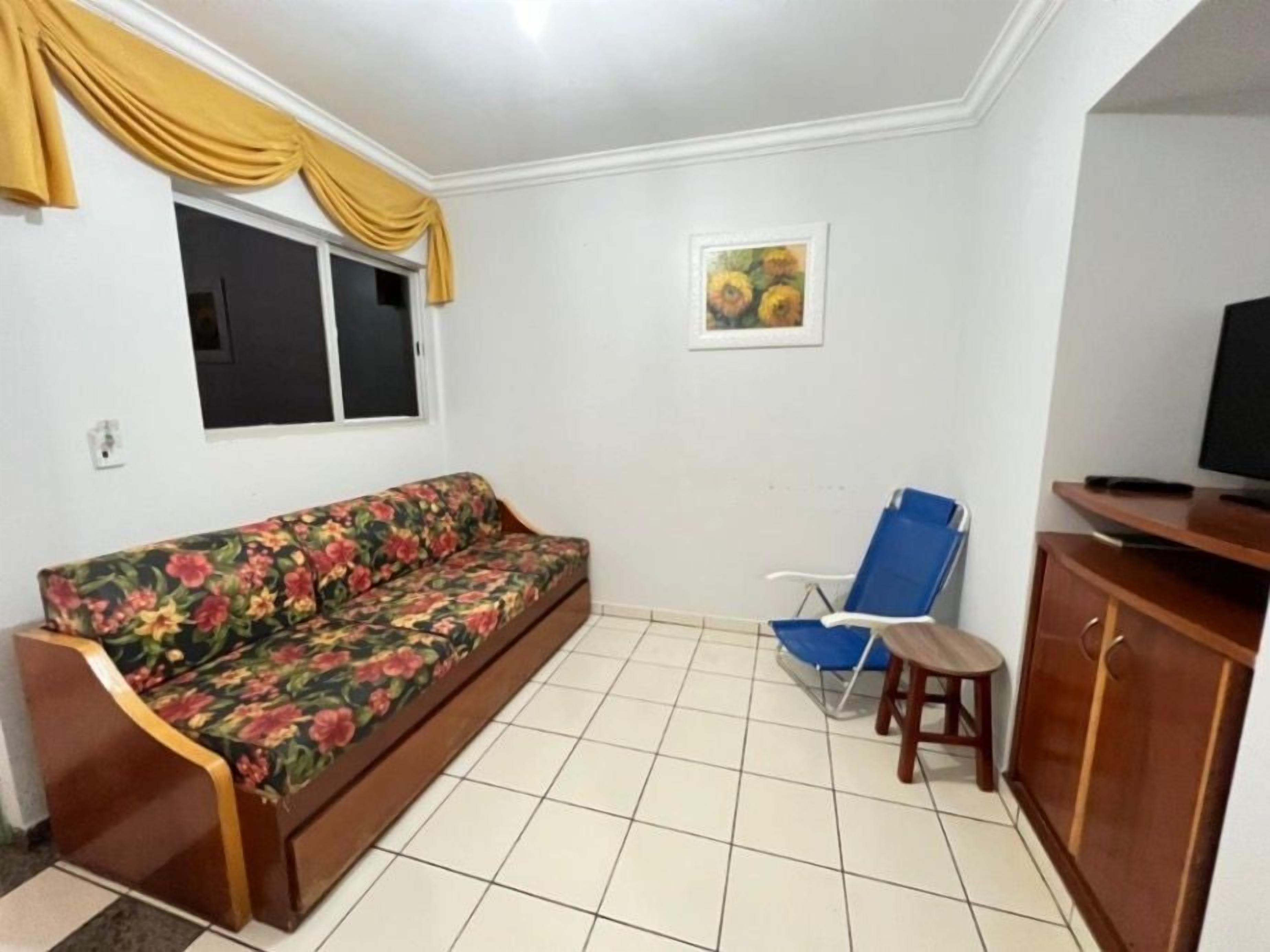Una habitación con sofá, una silla azul, televisor y aparador.