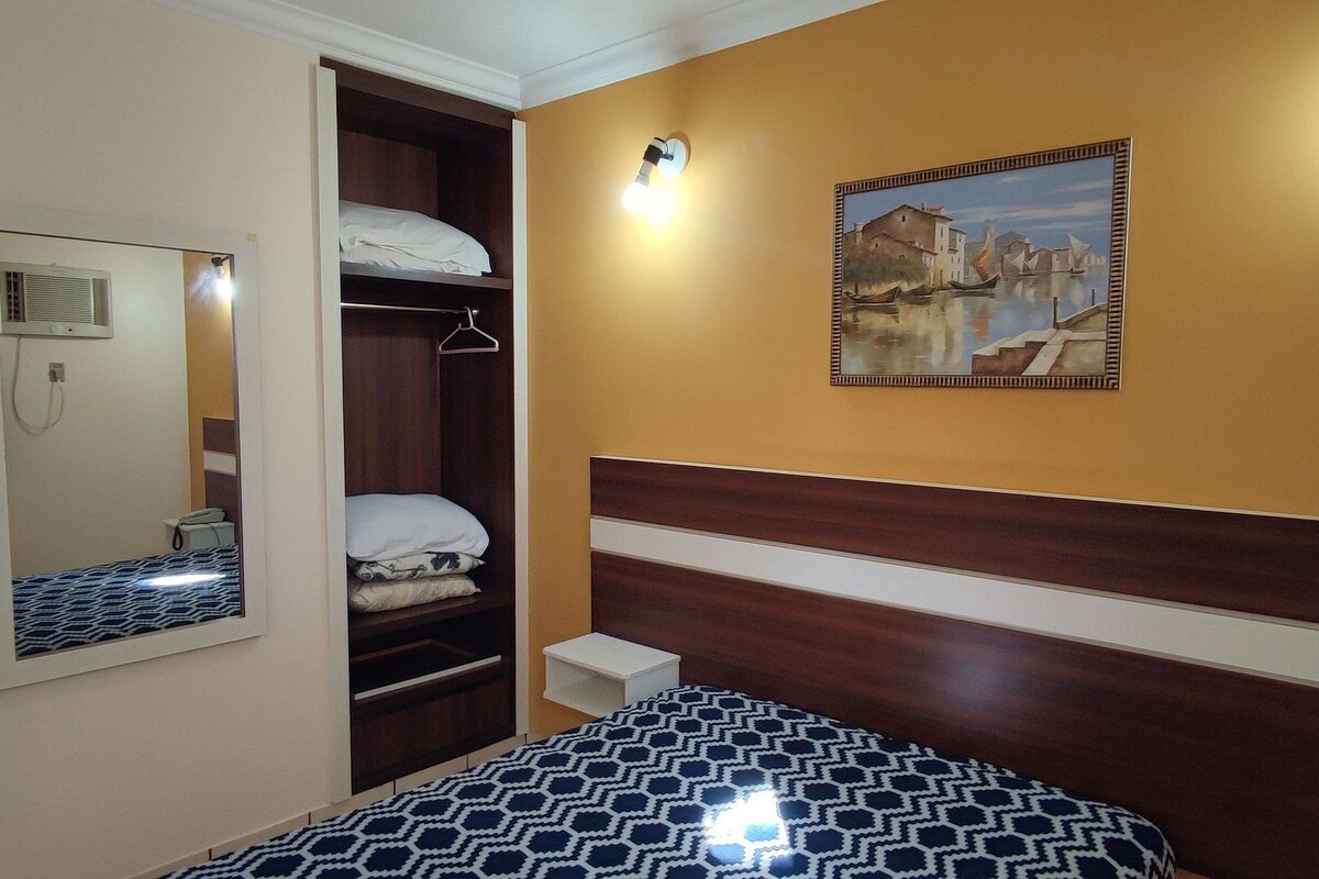 Ein Schlafzimmer mit Bett, Wandschrank, Nachttisch, Spiegel und einem Bild an der Wand.