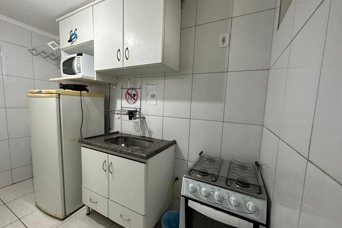Eine kleine Küche mit Kühlschrank, Mikrowelle, Spüle und Herd.
