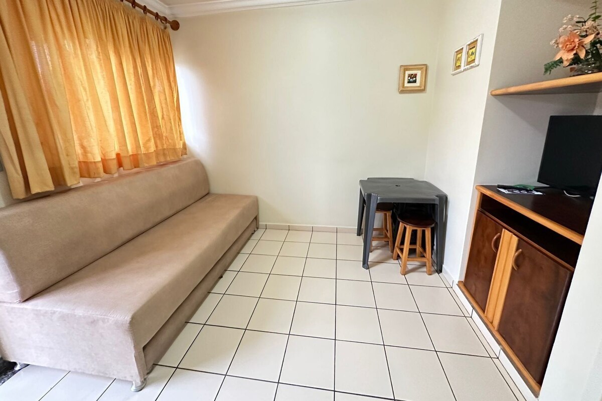 Ein Wohnzimmer mit einer Couch, einem kleinen Tisch, einem Fernseher und einem Schrank.