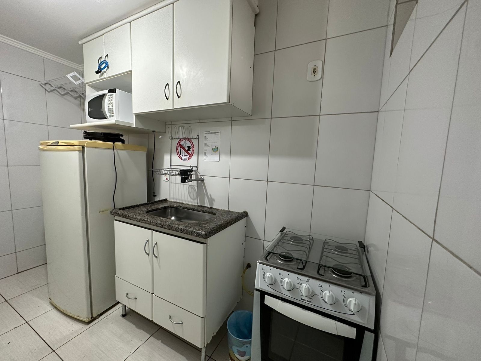 A compact kitchen with a refrigerator, microwave, sink, and stove.