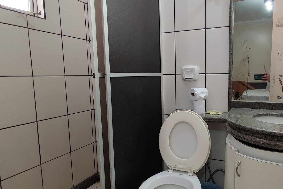 Ein Badezimmer mit Toilette, Waschbecken, Spiegel und gefliesten Wänden.