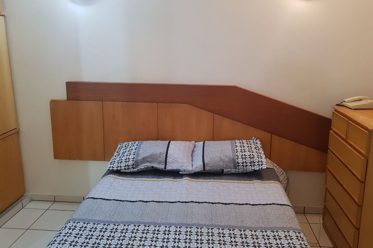 Ein Schlafzimmer mit einem Bett, einem Holz-Kopfteil, Nachttischen und Wandleuchten.