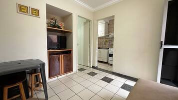 A compact living space with a kitchenette, a dining area with a table and stools, and a TV.