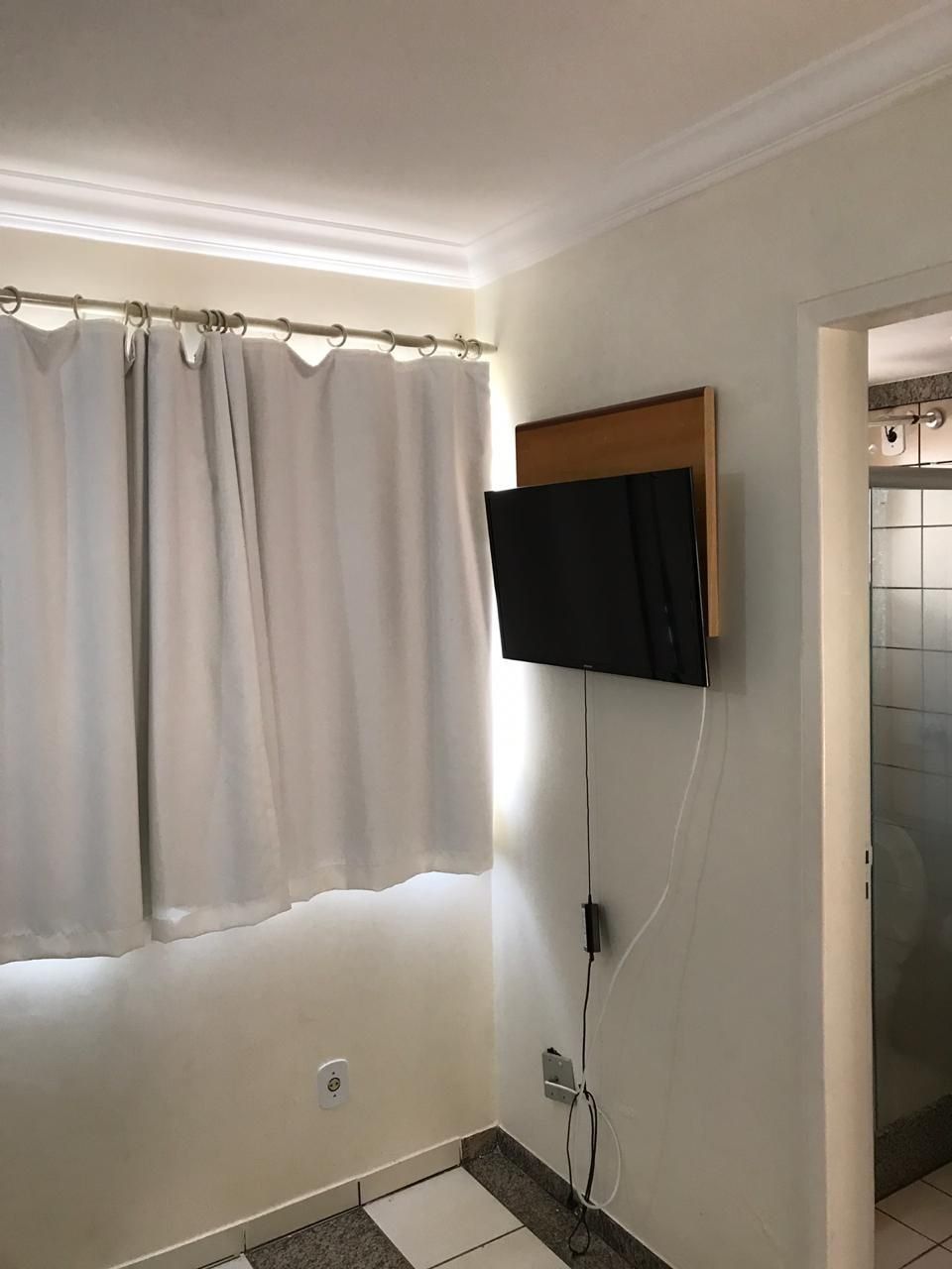 Un baño con ducha, inodoro y televisor montado en la pared.