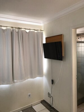 Une salle de bain équipée d’une douche, de toilettes et d’un téléviseur fixé au mur.